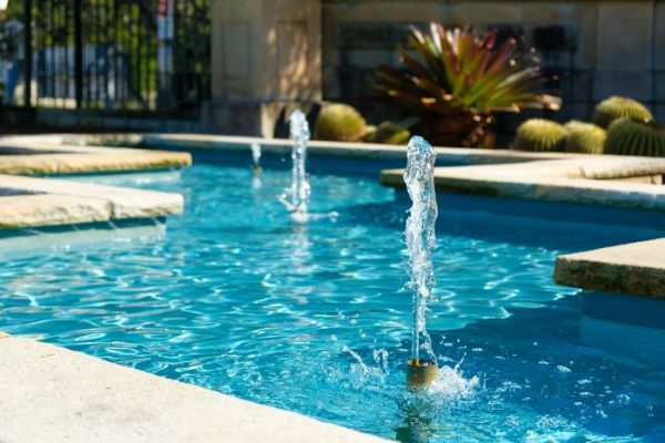 Crisp water jets rising from a blue tiled garden fountain, highlighting the aesthetic and tranquil benefits of water features in outdoor spaces.