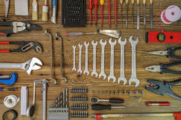 A meticulously organized array of essential hand tools laid out on a wooden surface, showcasing a variety of wrenches, screwdrivers, pliers, and measuring tools necessary for every homeowner's toolkit.