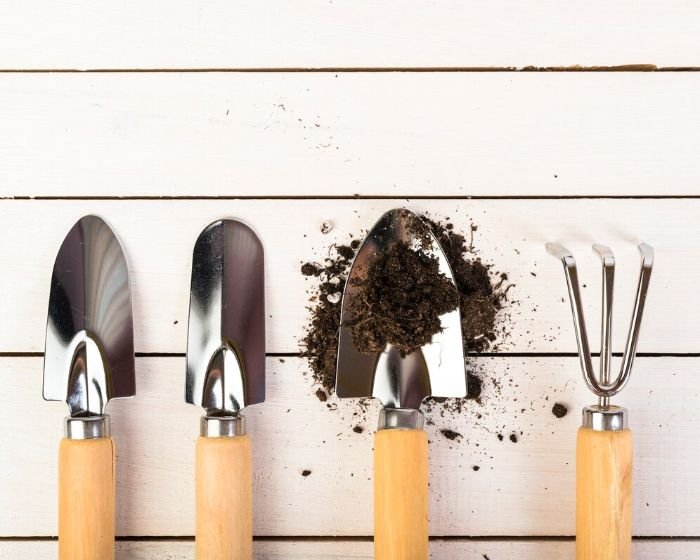 A set of four garden trowels with wooden handles arranged neatly on a white wooden surface, illustrating a buyer’s guide for choosing the right garden trowel.