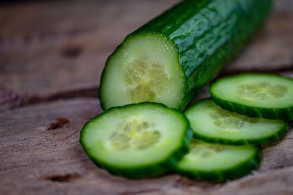 Freshly sliced cucumber on a wooden surface, highlighting the lush texture and vibrant interior, perfect for illustrating a guide on cucumber growth phases and cultivation tips.