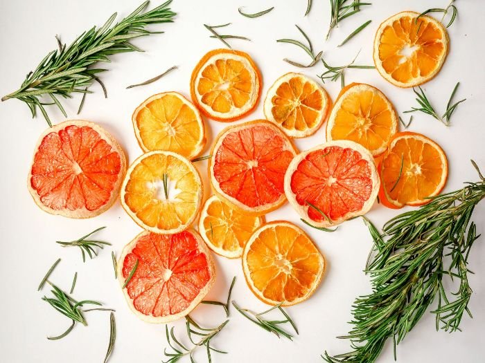 Slices of various citrus fruits, such as oranges and grapefruits, arranged with sprigs of rosemary, illustrating the versatile culinary and non-culinary uses of citrus fruits.