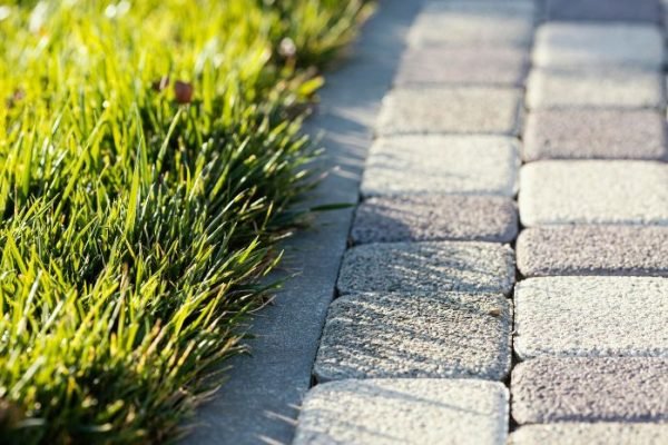 Close-up of a neatly arranged stone pathway bordered by lush green grass, highlighting the use of durable materials for creating both functional and aesthetically pleasing garden pathways.