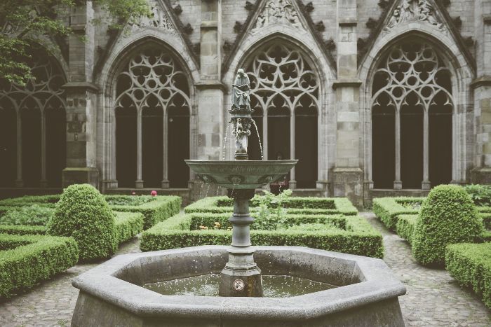 Majestic fountain with a classical sculpture in the center of a large formal garden with meticulously manicured hedges, illustrating how a grand fountain can serve as a focal point in expansive garden settings.