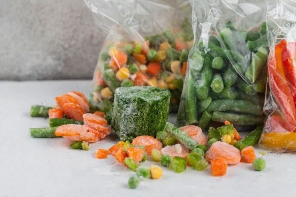 Assorted frozen vegetables, including carrots, green beans, and mixed veggies, in plastic bags, illustrating the process of freezing vegetables to retain freshness and nutrients.