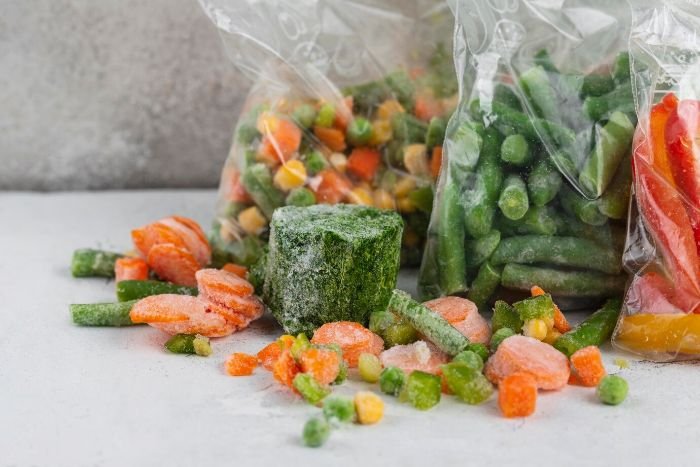 Assorted frozen vegetables, including carrots, green beans, and mixed veggies, in plastic bags, illustrating the process of freezing vegetables to retain freshness and nutrients.