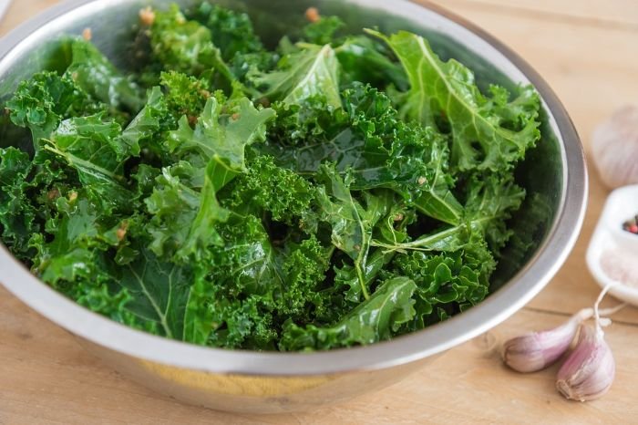 Fresh kale salad in a stainless steel bowl, prepared with garlic, emphasizing kale's role in weight management due to its low-calorie and high-fiber content, perfect for healthy diets.