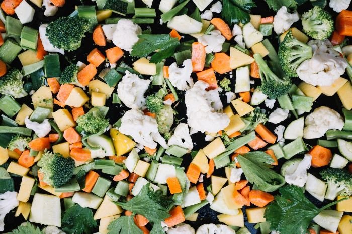 An assortment of diced and chopped vegetables, including broccoli, cauliflower, carrots, and squash, spread out evenly, illustrating solutions for common drying mistakes.