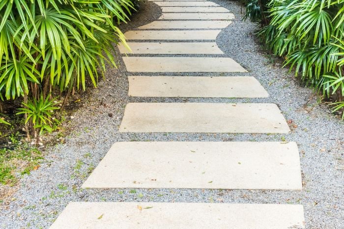 Elegant garden pathway made with smooth stone slabs surrounded by lush foliage, illustrating the use of materials like granite, slate, and limestone for durable and aesthetically pleasing outdoor walkways.