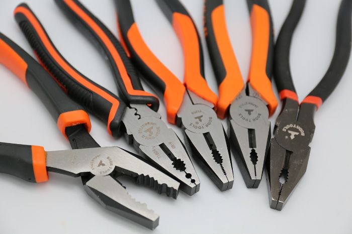 Close-up of various types of pliers with orange and black ergonomic handles, showcasing different designs suited for gripping, cutting, and bending, essential for effective task execution in home improvement projects.