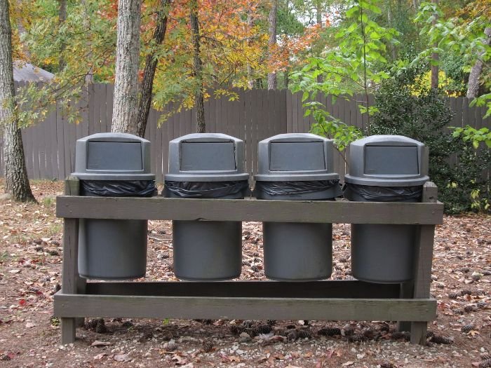 Four compost bins set up in a wooden frame in a garden, illustrating optimal placement and setup for new compost bins in a sunny, accessible spot with well-drained ground.