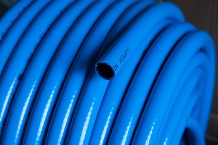 Close-up of a coiled blue specialty garden hose, illustrating the different features and specific needs these hoses can meet, such as heavy-duty watering, lightweight use, or safe drinking water.