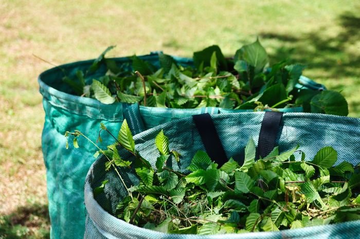 Two tumbler bins filled with green garden waste, illustrating the pros and cons of using tumbler bins for composting, such as ease of turning and aeration.