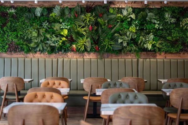 Modern vertical garden design with lush greenery in a restaurant setting, showcasing an eco-friendly and stylish interior feature.