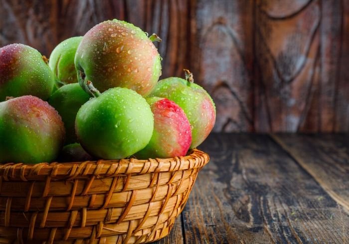Basket of fresh homegrown apples with water droplets, highlighting the heart-healthy benefits of incorporating apples into your diet.