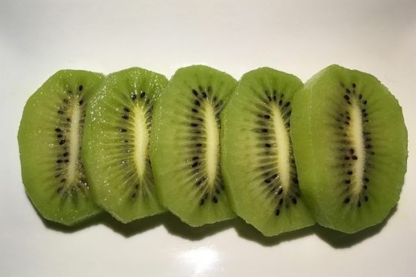 Close-up of sliced homegrown kiwiberries showcasing vibrant green flesh and nutrient-rich seeds high in omega-3 fatty acids.
