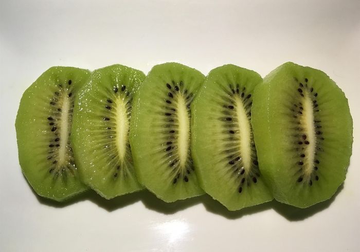 Close-up of sliced homegrown kiwiberries showcasing vibrant green flesh and nutrient-rich seeds high in omega-3 fatty acids.