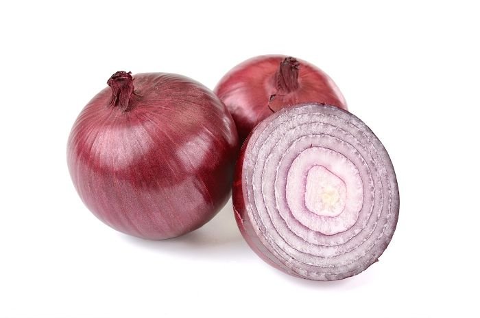 A close-up image of fresh onions on a wooden surface, emphasizing their health benefits, from fighting inflammation to reducing cancer risk.