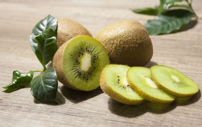 Whole and sliced kiwifruit rich in Vitamin K, promoting bone health and showing the benefits of growing your own fruit at home.