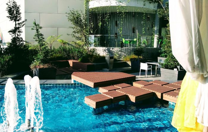 Modern garden design featuring wooden platforms and a water fountain, showcasing planning and care for water features in outdoor spaces.
