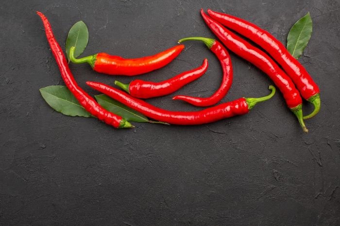 Red chili peppers on a dark background, illustrating potential side effects and precautions when consuming spicy foods, including managing spiciness, allergic reactions, and digestive considerations.