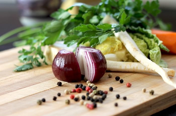 Chopped red onion on a cutting board with fresh herbs, showcasing the role of onions in blood sugar regulation and diabetes management.