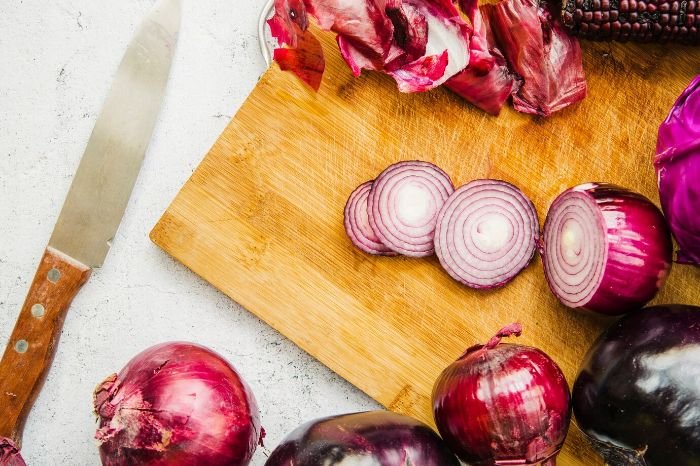Sliced red onions on a cutting board, showcasing their versatility in culinary uses, from raw salads to cooked dishes.