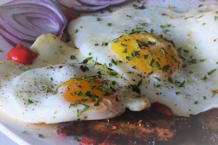 Close-up of eggs with sautéed onions and herbs, highlighting the digestive health benefits of onions due to their dietary fiber content.