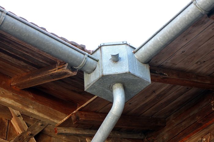Close-up of a rainwater gutter junction on a wooden house, showing setup for overcoming common rainwater harvesting challenges
