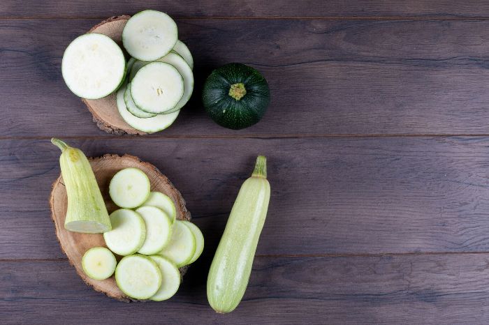 Various types of sliced zucchini on wooden slices, showcasing its high water content that helps with hydration and feeling full while keeping calories low.