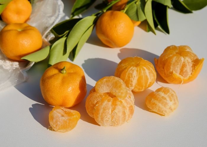 Fresh and peeled citrus fruits on a table, highlighting the versatility of citrus in recipes like salads, roasted chicken, glazed salmon, and desserts.