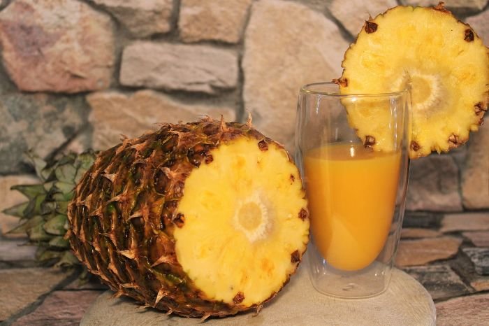 Freshly cut pineapple and a glass of pineapple juice, highlighting the fruit's dietary fiber benefits for digestive health.