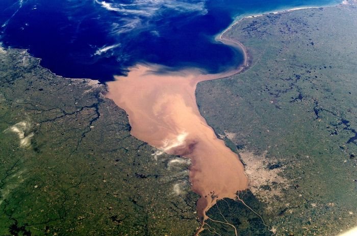Aerial view of a river merging with the ocean, symbolizing challenges in integrating satellite data for accurate crop forecasting.