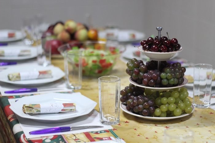 Table set with dishes and a tiered fruit stand featuring freshly harvested grapes, showcasing the process of harvesting and using homegrown grapes.