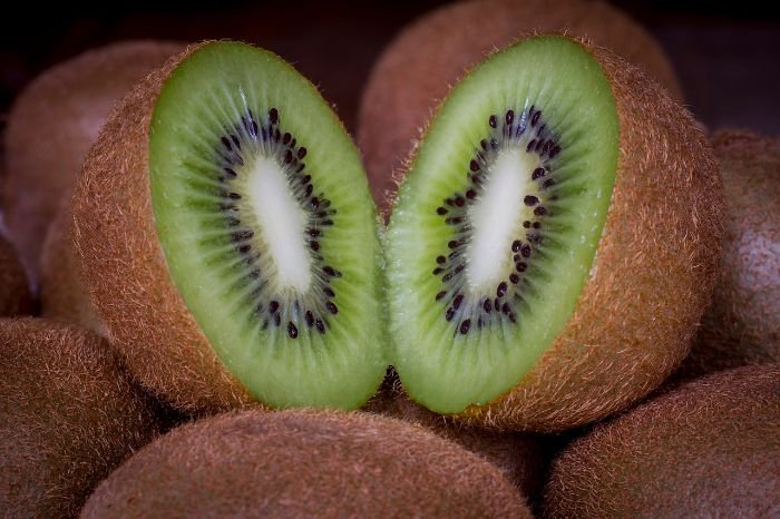Freshly harvested kiwifruit cut in half, showing vibrant green flesh and seeds, ready for consumption or use in recipes.