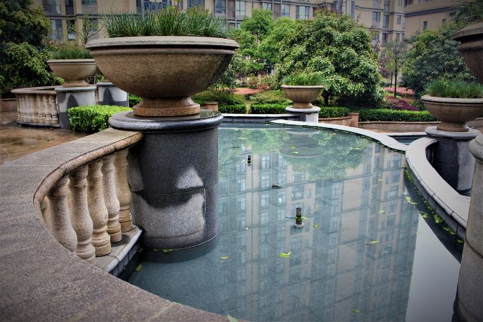 Garden water feature with stone planters and reflecting pool, illustrating planning and design for adding a water feature to a garden space.