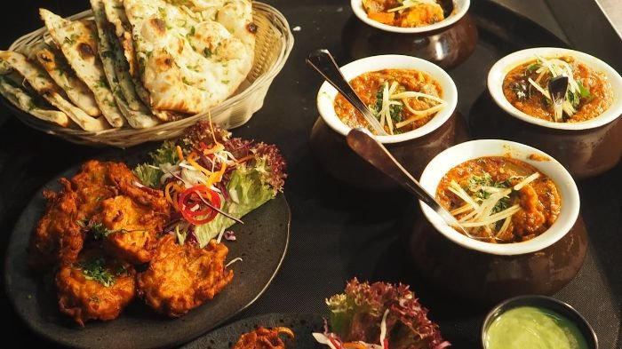 An assortment of flavorful dishes, including curries, naan bread, and appetizers, beautifully arranged on a table, perfect for a well-planned dinner party menu.