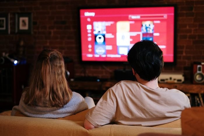 Two people watching a smart TV in a cozy living room while optimizing picture and sound quality for an immersive viewing experience.