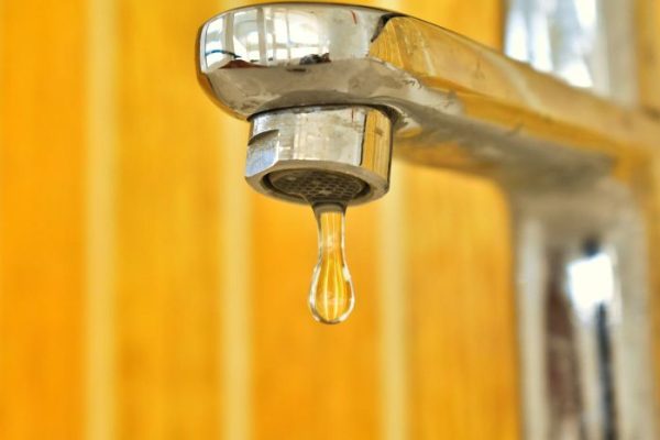 Close-up of a leaky faucet dripping water, illustrating the need for step-by-step guidance on fixing leaky faucets in a household.