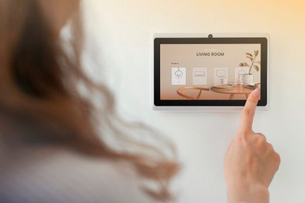 Person adjusting a smart thermostat on a wall-mounted screen, illustrating how smart thermostats help optimize heating and cooling for energy efficiency and comfort.