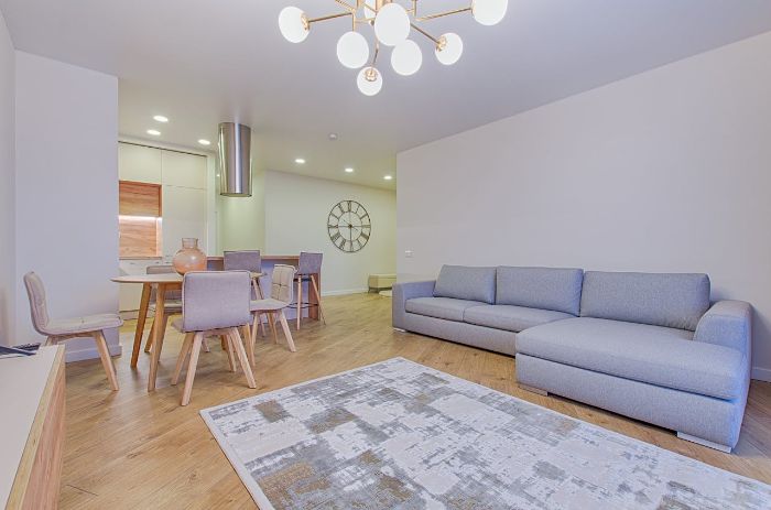 Minimalist living room decor with a grey sectional sofa, modern chandelier, and wooden dining area for a peaceful and clutter-free space