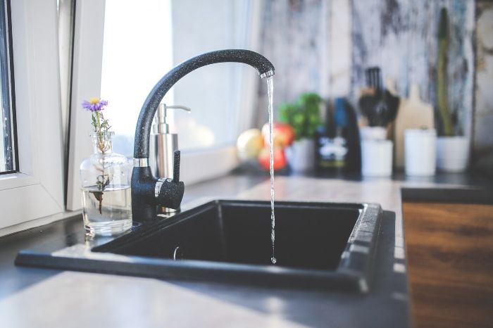 A modern kitchen faucet with running water, emphasizing the importance of preventative maintenance to prolong faucet life and prevent leaks.