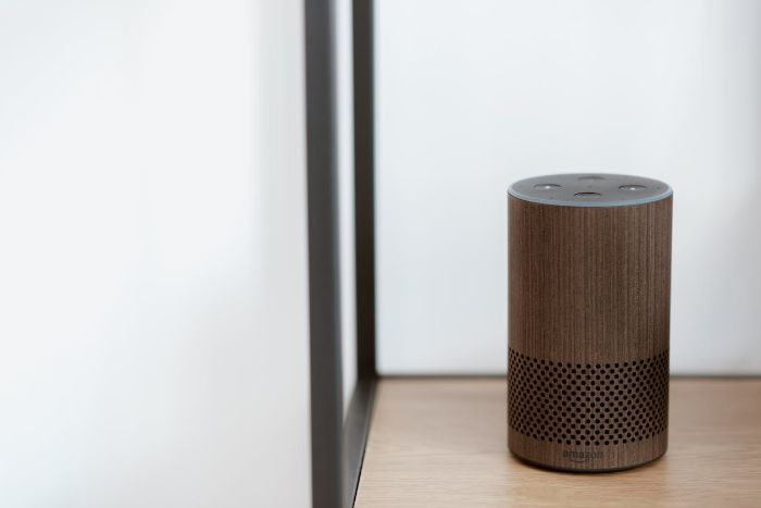 Close-up of a voice-activated smart speaker on a wooden shelf, highlighting the importance of privacy and security in managing voice data and addressing user interaction concerns.
