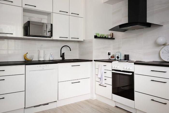 Modern kitchen with sleek white cabinets, illustrating the benefit of using pull-out racks to easily access heavy pots and pans, enhancing organization and efficiency.