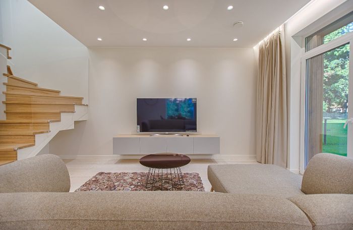 Minimalist living room with neutral tones, tidy decor, and ample open space, exemplifying room-by-room decluttering for a calm and organized home environment.