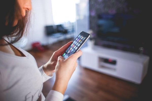 Woman using smartphone to control smart home devices, illustrating mobile-based interaction in beginner-friendly smart home ecosystems.