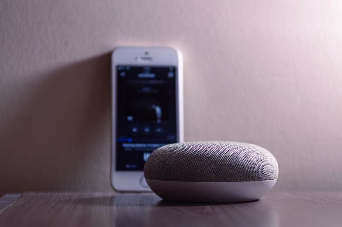 Voice-activated smart speaker paired with a smartphone, showcasing its role in seamless smart home integration for controlling devices like lights, thermostats, and security systems.