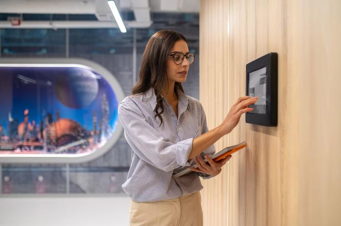 Woman interacting with a smart security panel on a wall, illustrating top smart lock recommendations for enhanced home safety