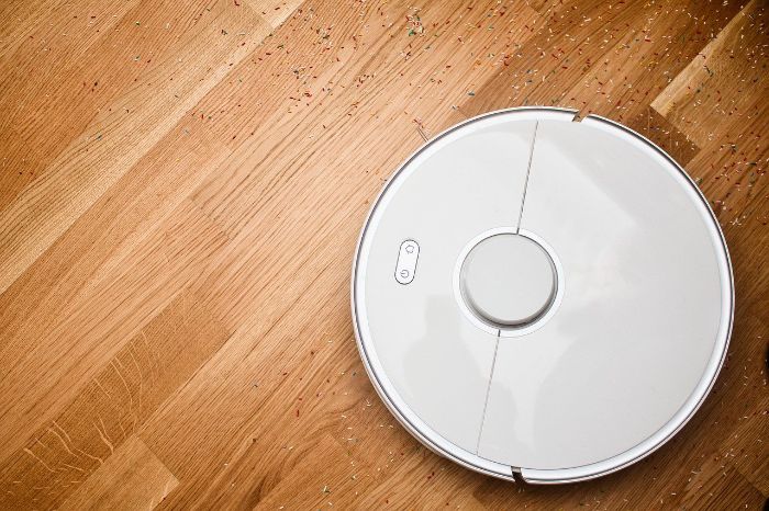 Robotic vacuum cleaner efficiently cleaning a wooden floor, highlighting time-saving cleaning gadgets for busy lifestyles.
