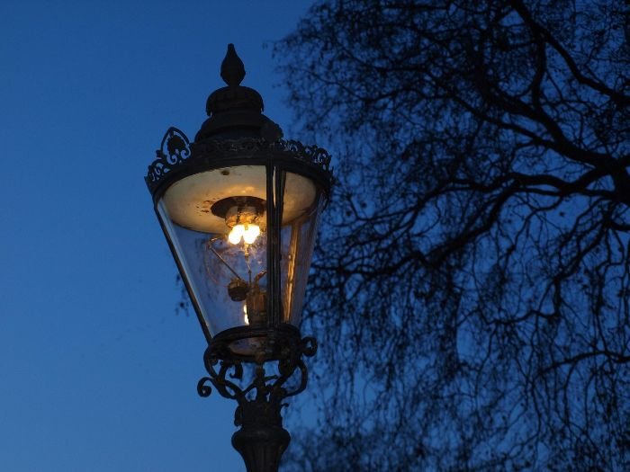 A vintage-style pathway lamp glowing at dusk, illustrating common troubleshooting issues like bulb maintenance and wiring checks.