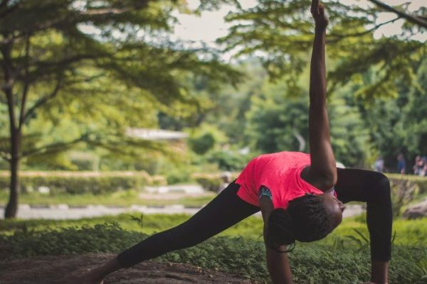 Person stretching outdoors in a garden-like setting, symbolizing how gardening activities can improve physical flexibility and body movement.